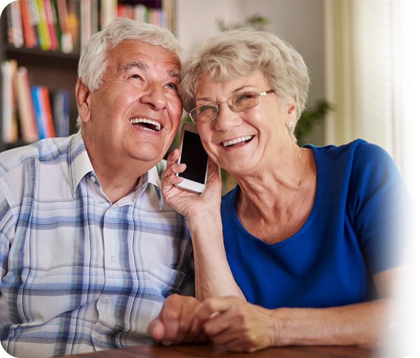 Elderly couple smiling and pointing at a smartphone
